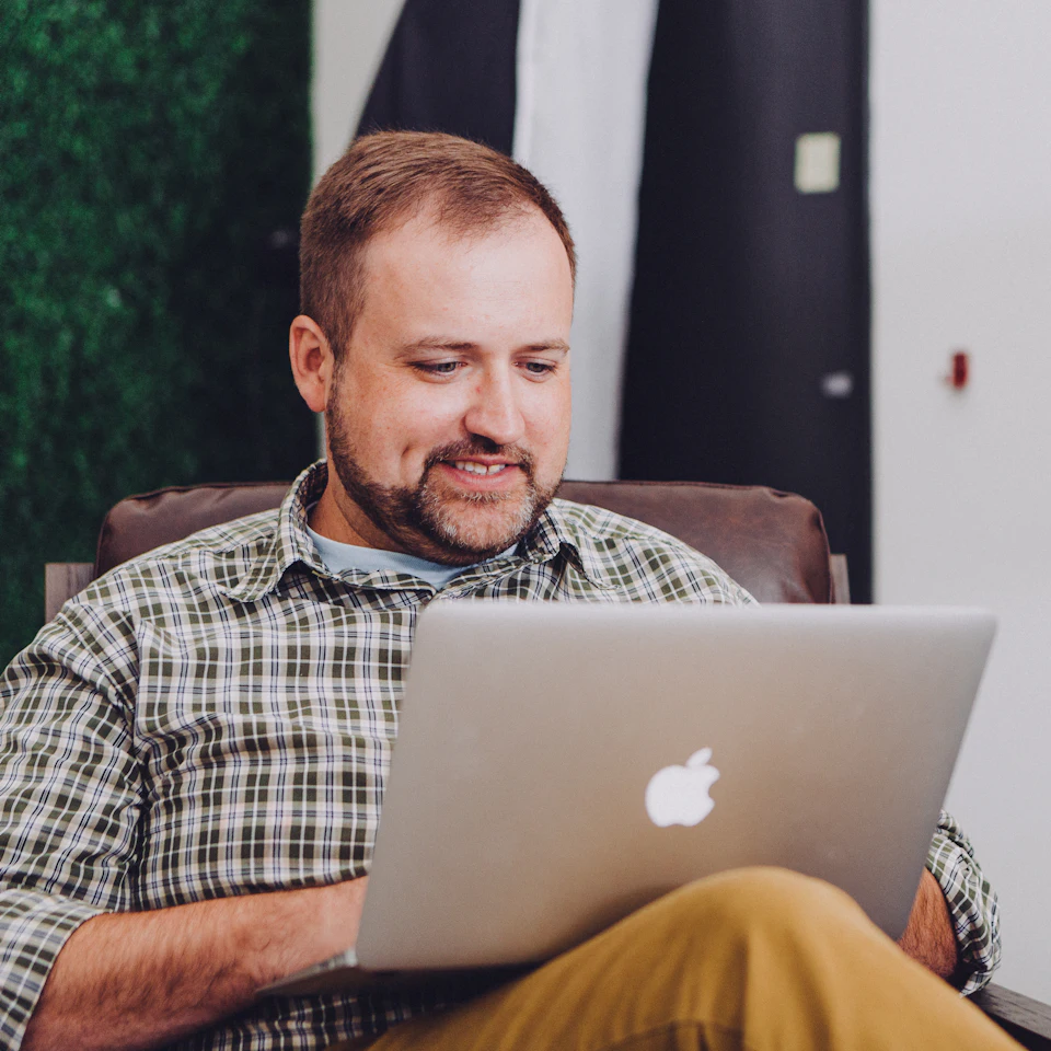 Empreendedor sorrindo enquanto cuida do site no notebook