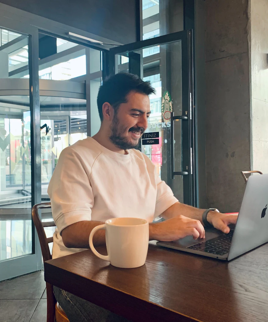 Empreendedor sorrindo enquanto trabalha no notebook em um café